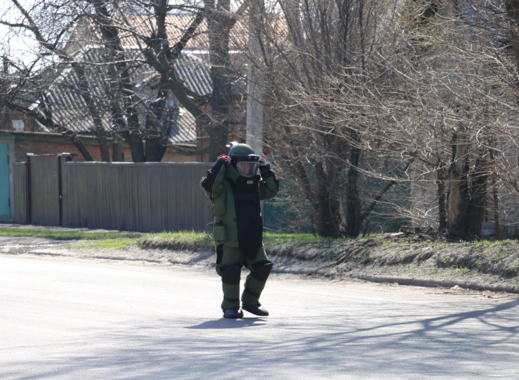 Deminer in a protective suit walking along a village road