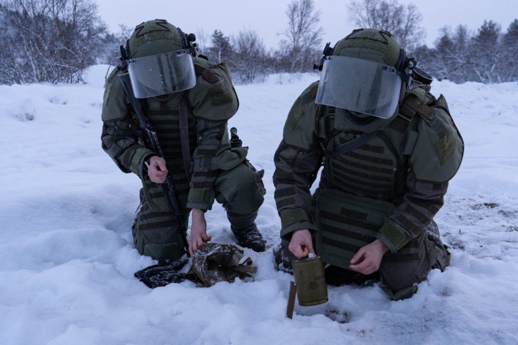 Military engineer kneeling in snow during a demining exercise