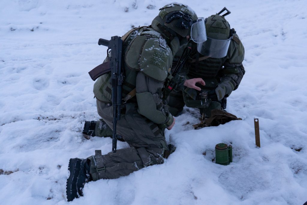 Military engineers handling ordnance during a winter demining exercise