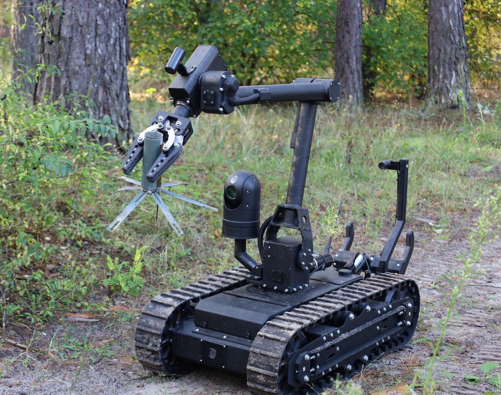 Remote-controlled demining robot with a manipulator arm in the forest